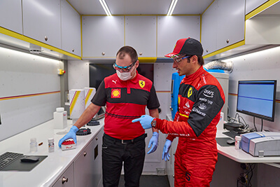 Race car driver holding a bottle of Shell Helix Ultra, which contains carbon-neutral lubricants