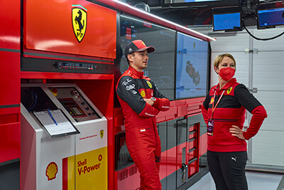 V-Power team wearing driver gear with helmet looking at dashboard analysis and metrics for racing performance